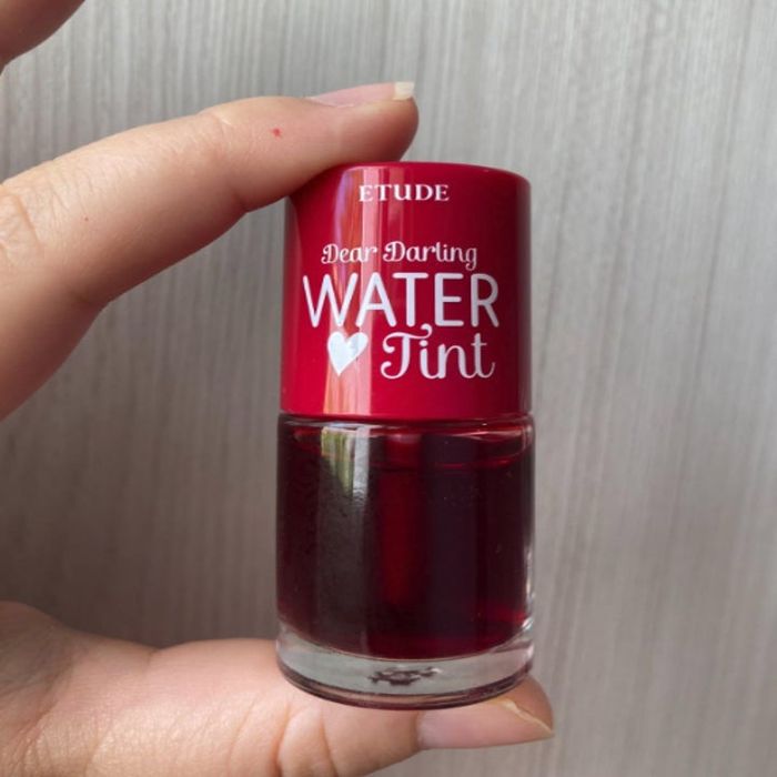 A hand holding the Etude Dear Darling Water Tint, a beloved skincare product known for its lightweight texture.