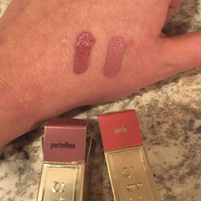 Two lipstick swatches on a hand, accompanied by two lipstick tubes labeled