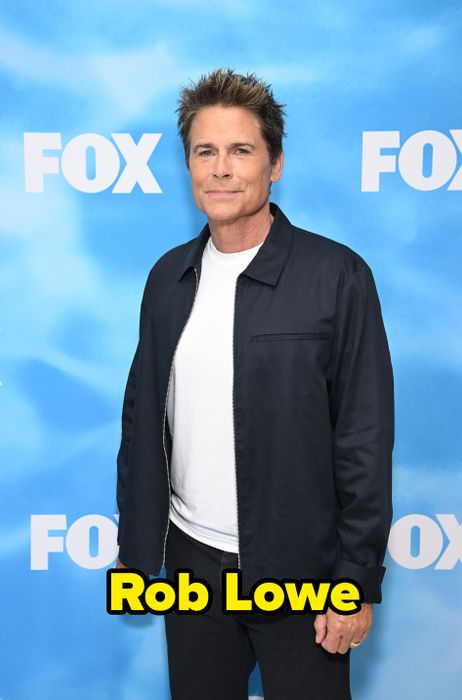 A person dressed in a casual black jacket and white shirt, standing in front of a backdrop with the
