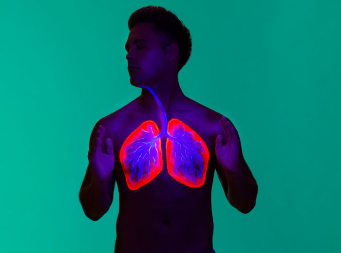 Person holds their hands up, with digitally illustrated lungs visible on the chest against a green background