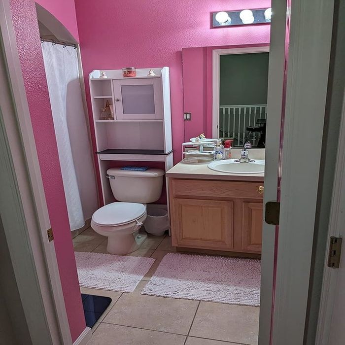 A small bathroom with an over-the-toilet shelf neatly organized.
