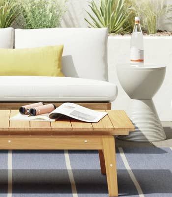 The white table placed next to a patio couch with a bottle of water on top.