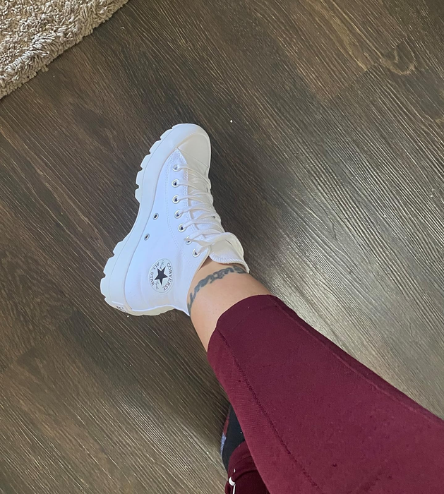 Reviewer wearing high-top white Converse sneakers with the iconic star logo, matched with burgundy trousers
