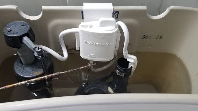 A reviewer shows off their toilet tank's cleaning cartridge system in action.