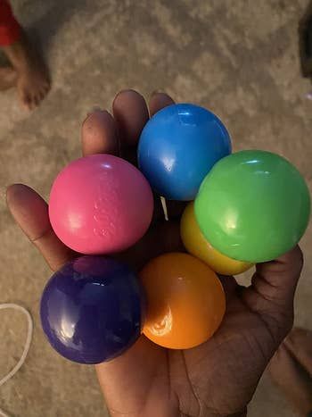 A photo showing the reviewer holding six colorful globbles in their hand.