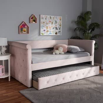 The same pink velvet trundle bed, with the trundle pulled out to provide extra sleeping space.
