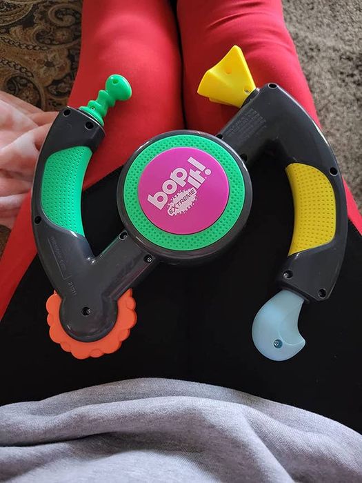 A reviewer shows their Bop It sitting on their lap