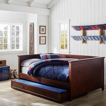 An espresso wood daybed with a trundle feature, offering a sleek and functional design.