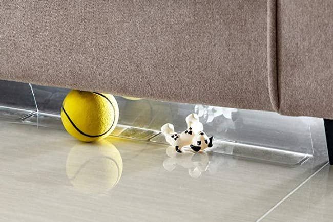 Toys being prevented from rolling under the couch by the blocker