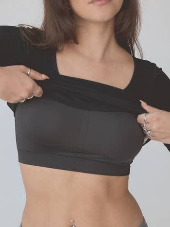 A person wearing a black crop top layered under a shirt, showcasing the outfit for a shopping-focused fashion article.