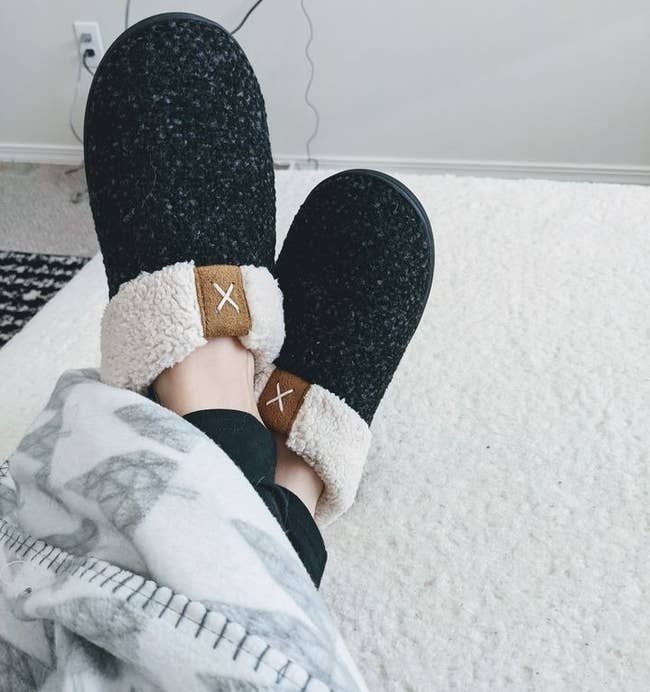 A reviewer wearing the black sherpa-lined house slippers