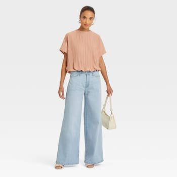 A model sporting wide-leg light blue jeans.