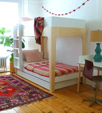 A trundle bunk bed placed in a child's room, complete with a ladder for easy access to the top bunk.