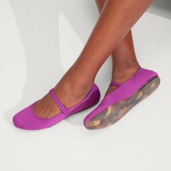 A model shows off bright pink mary jane flats with stylish crisscross straps.