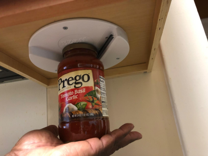 A reviewer using the opener to effortlessly open a jar of sauce with just the palm of their hand