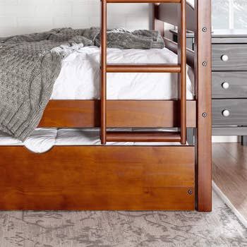 The trundle placed neatly under a matching wooden bunk bed, creating an efficient sleeping arrangement.