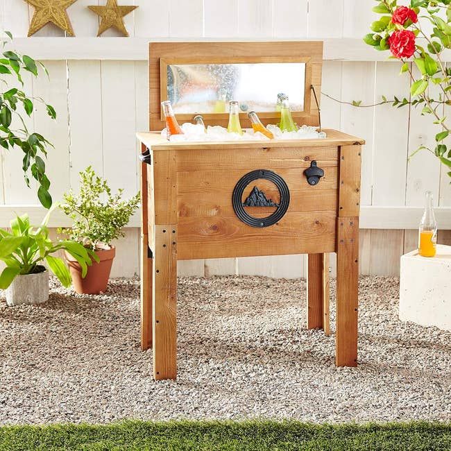 A portable wooden outdoor bar station equipped with a convenient storage shelf and a metal towel holder, perfect for your outdoor gatherings.