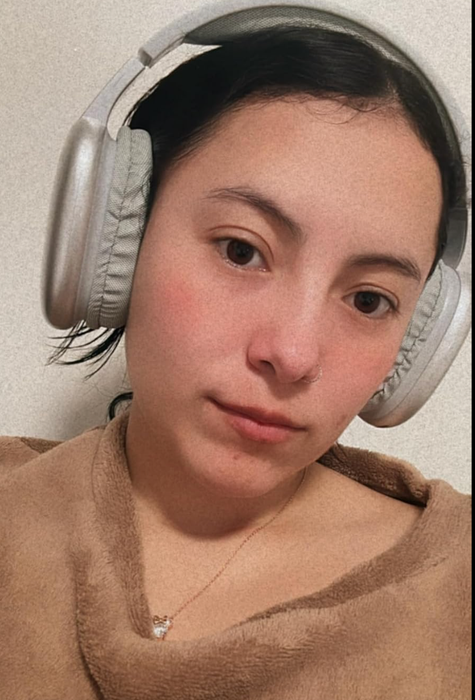 A model wearing soft gray over-ear headphones, fully padded for comfort.