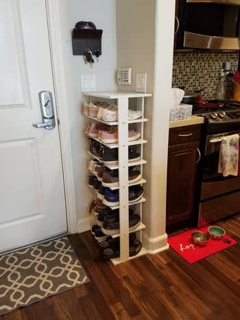 A reviewer showing the side view of the shoe tower, demonstrating how its slim design allows it to fit perfectly beside a door.