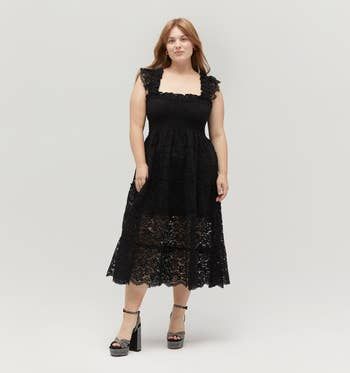 A person rocking a sleeveless lace dress with platform heels, striking a pose against a simple background.