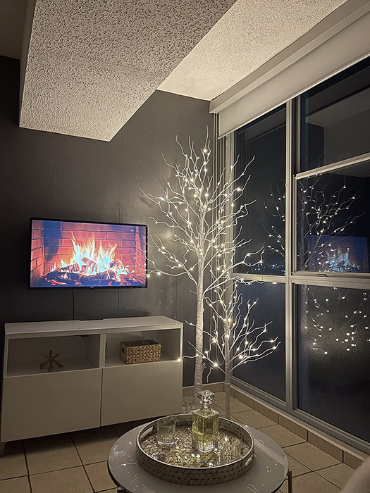 Reviewer photo featuring two glowing faux birch trees set up in their cozy living room