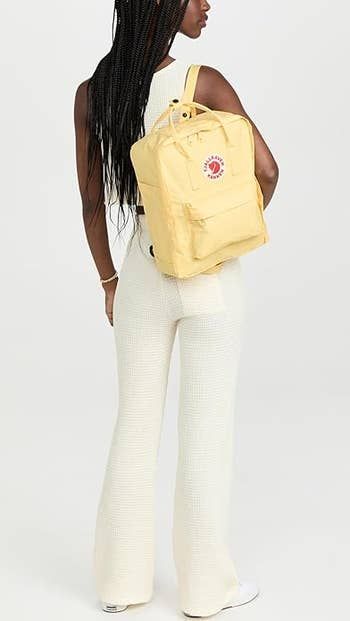 A model showcasing the backpack in a soft yellow shade.
