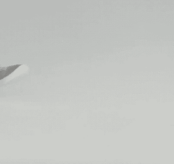 a gif of a model wearing the light gray sneakers