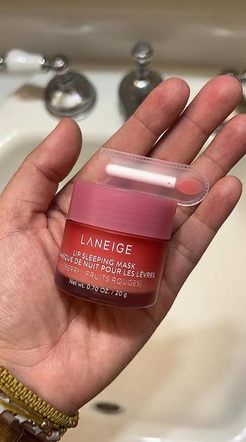 A reviewer is holding the jar of the lip mask along with the applicator.