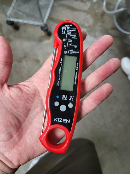 A reviewer holding the red and black thermometer with its probe neatly tucked away.
