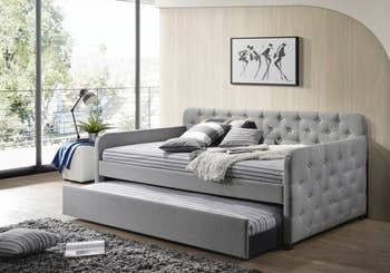 lifestyle image showcasing a gray upholstered daybed with trundle