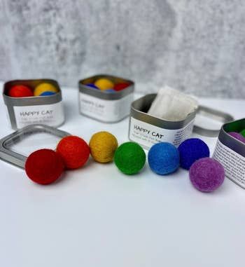 A colorful collection of felted balls displayed alongside metal tins