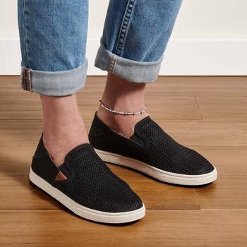 A model casually wearing the black Olukai sneakers, showcasing their effortless style.