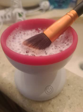 A reviewer cleaning a brush in the machine with foamy water inside.