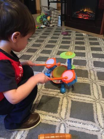 A reviewer's child enjoying a fun time on the compact drum set.