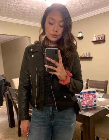 A reviewer styling the black jacket with a pair of jeans