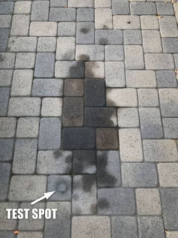 A large, stubborn stain on the reviewer's paver stones, with a clean test spot visible.