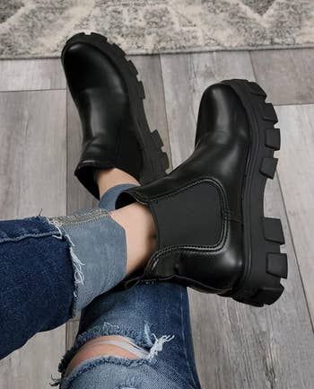 A person wearing black platform boots with jeans, captured from a top-down perspective