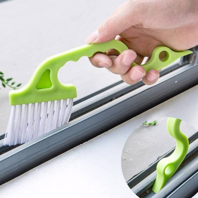 A slim, green-handled brush designed for cleaning tight spaces.