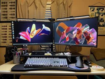 a reviewer’s sit-to-stand desk in the seated position, featuring two monitors, a keyboard, and a mouse