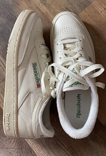 Two Reebok sneakers placed on a wooden floor, highlighting their retro design and iconic logo