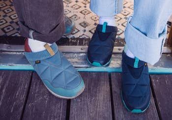 Two individuals standing in casual, quilted slip-on shoes on a wooden floor, the image featured in a shopping article.