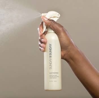 a hand spritzing the root refresh spray