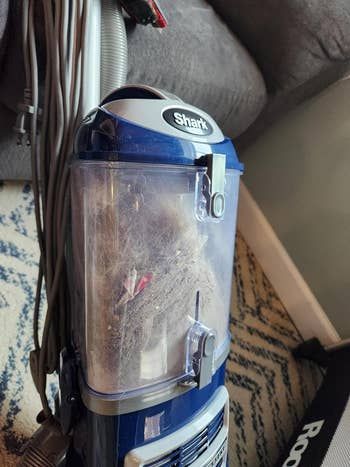 A vacuum filled with dirt and pet hair, showing the aftermath of cleaning.