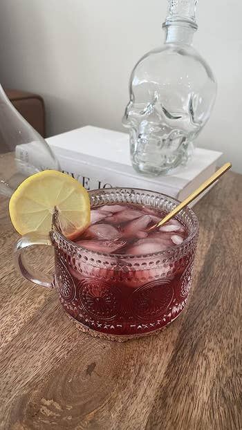 A glass mug featuring a subtle sunflower dot print, holding a refreshing glass of iced tea.