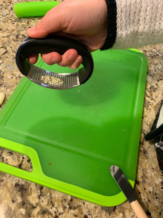 Close-up shot of a hand holding the garlic press tool