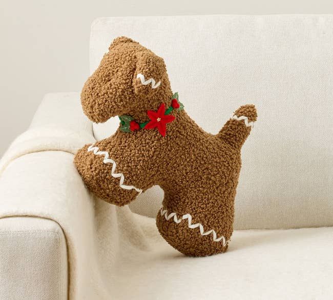 A plush gingerbread-shaped dog toy resting on a couch