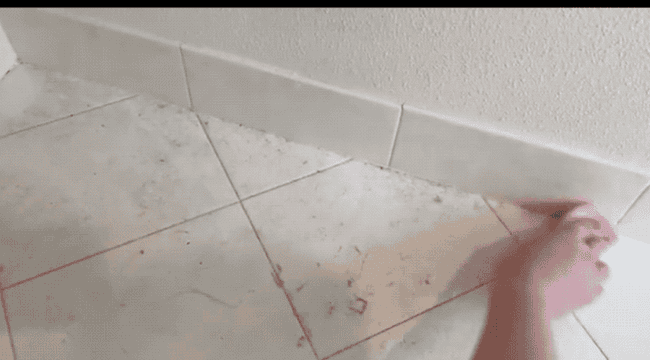 A gif of a reviewer wiping dust from a tile floor, demonstrating how it collects on the textured surface of the damp duster