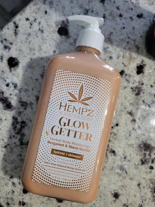 A bottle of Hempz Glow Getter body lotion, infused with bergamot and warm vanilla scent, resting on a marble surface