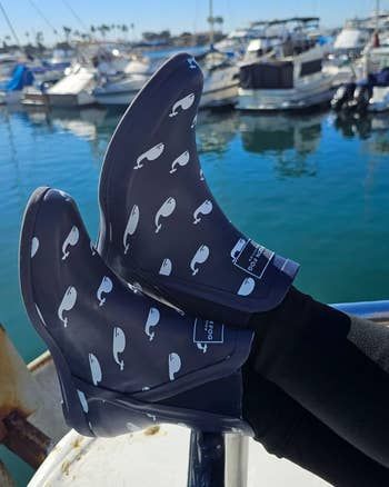 A reviewer is seen wearing blue rain boots featuring whale designs.