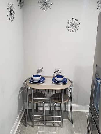 A reviewer's photo showcasing a silver bistro table with two matching chairs tucked neatly underneath